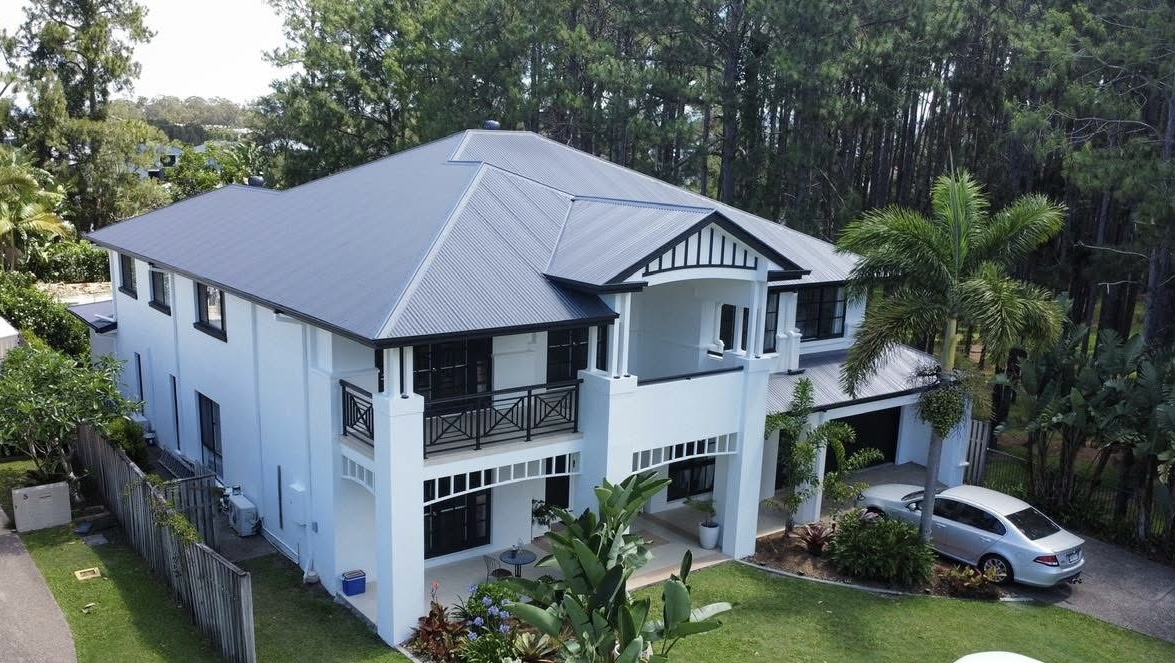 After: the same house with a charcoal roof, white walls and black trim